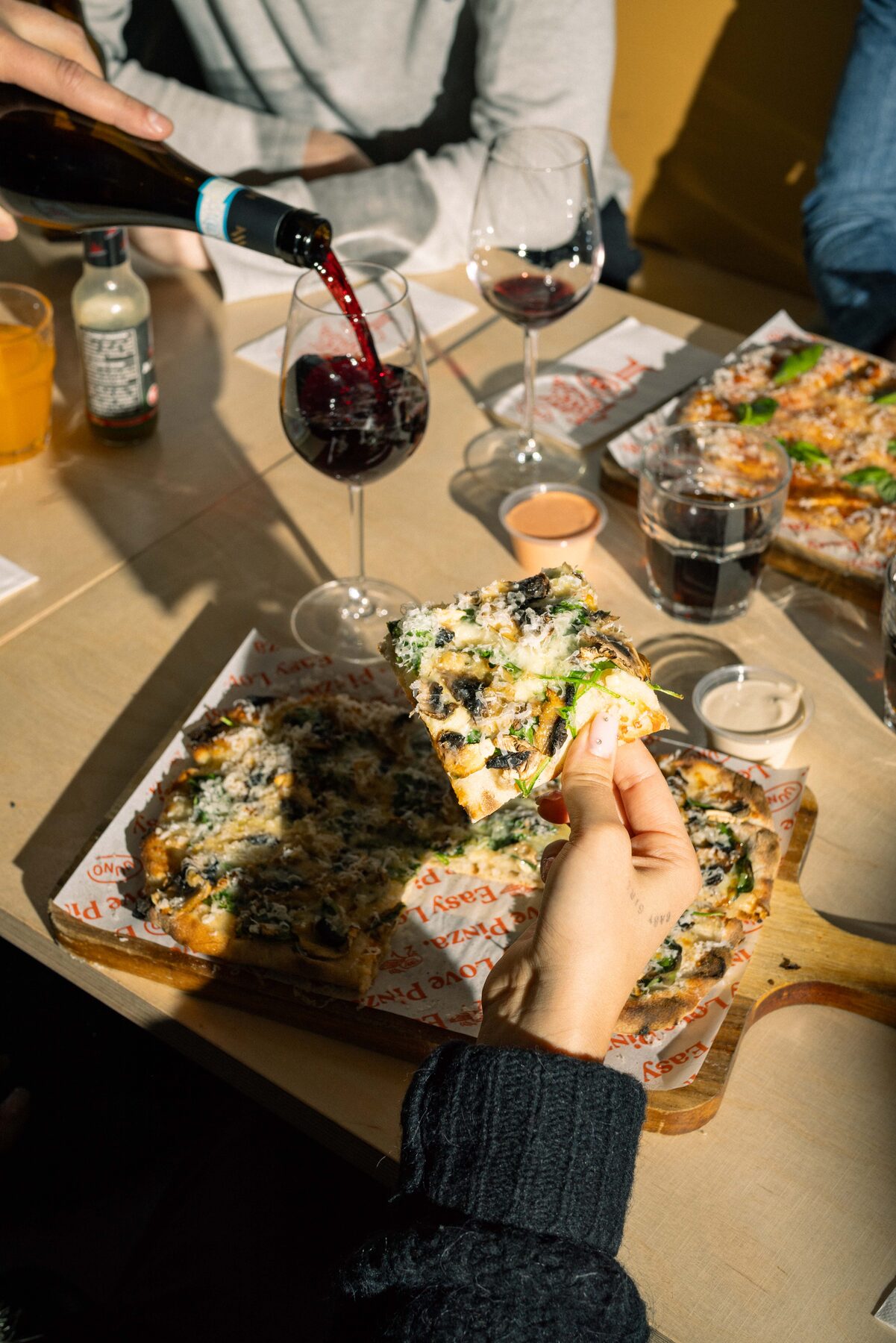 Uuno pizzeria — pinza on a wooden board, red wine glass, soft yellow string lights overhead.